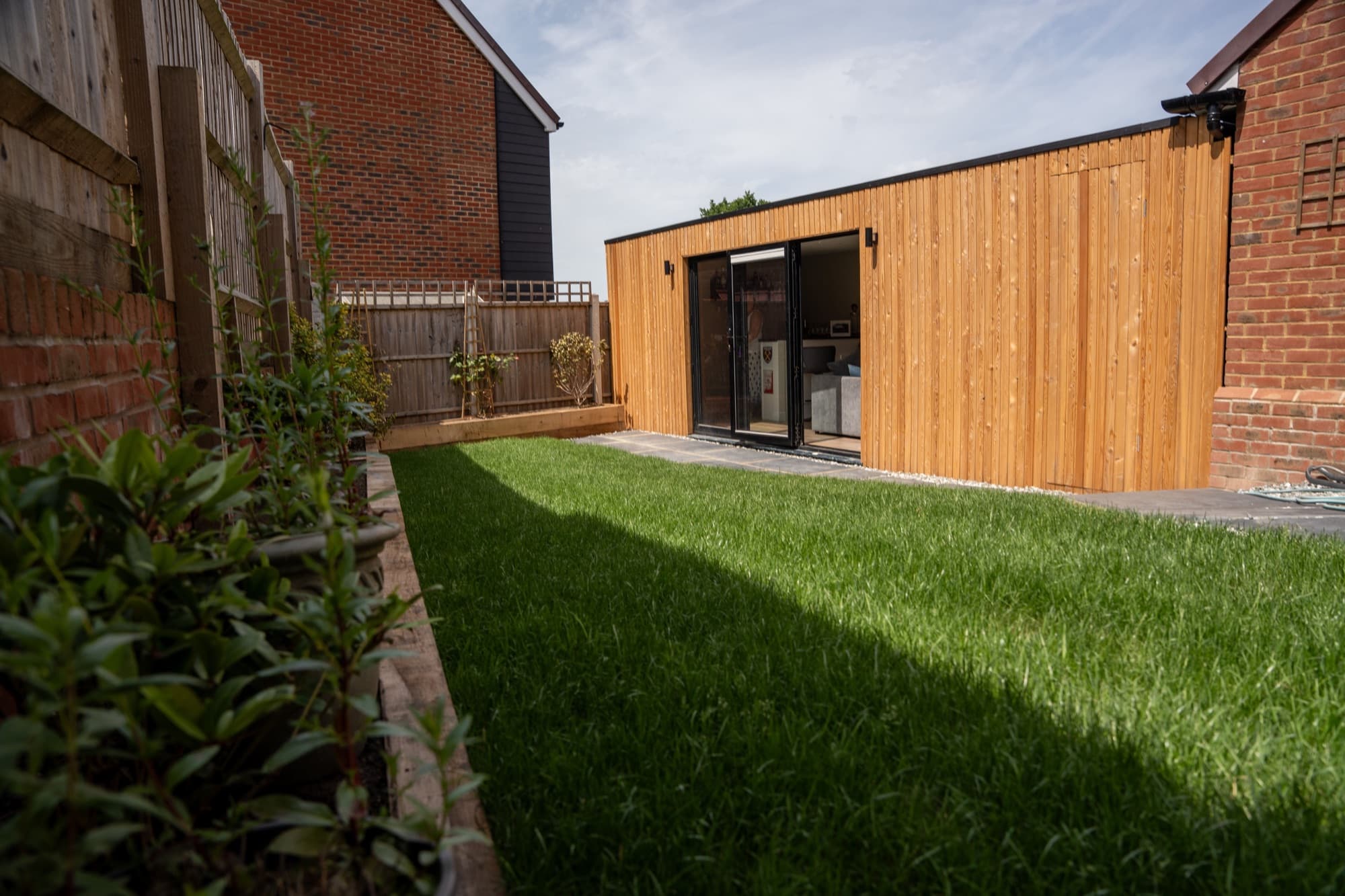 Timber garden room across a lawn, used as a garden office